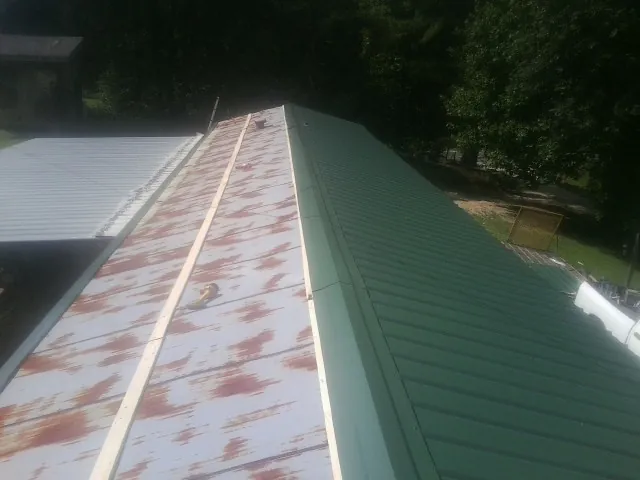 Old rusted panels beside newly installed green metal roofing — Wind Damage Roof Repair by Roofing Brothers in Stevenson
