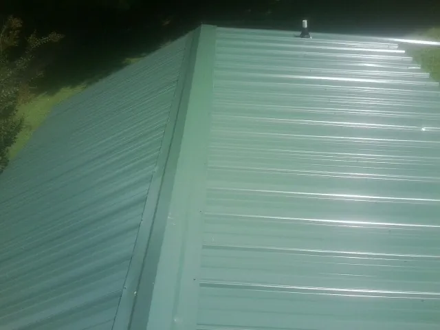 New green metal panels meeting at the ridge of a roof — Flat Roof Repair work by our crew in Stevenson